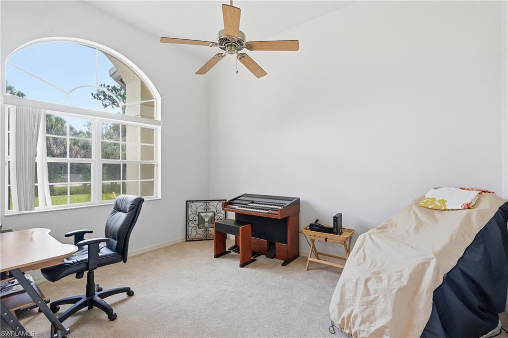 Arched window with multiple panes, vaulted ceilings, neutral wall color, and light-toned carpeting