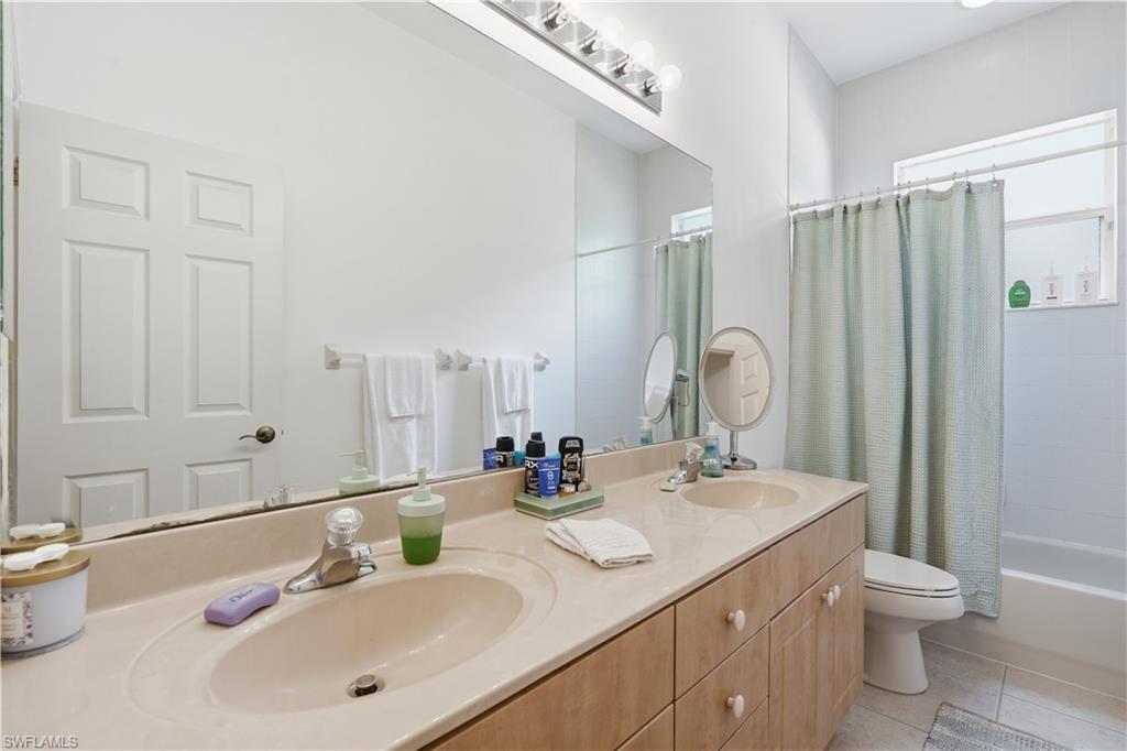 Dual sink vanity with a built-in countertop, light wood-finish cabinetry, and individual faucets