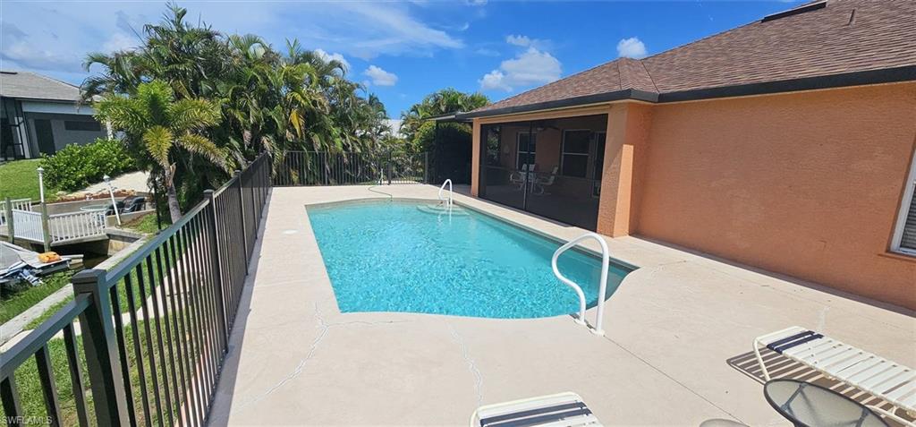 Rectangular swimming pool with integrated steps and handrails, surrounded by a concrete pool deck