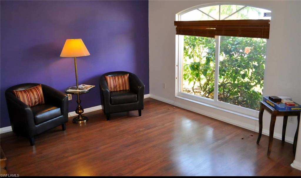 Room featuring wood-finish flooring, a prominent arched window with a wood blind, and a distinct accent wall