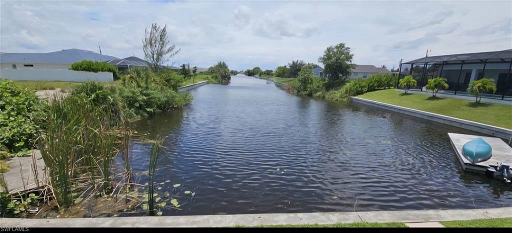 Waterfront property featuring a private dock, concrete seawall, and mature tropical landscaping