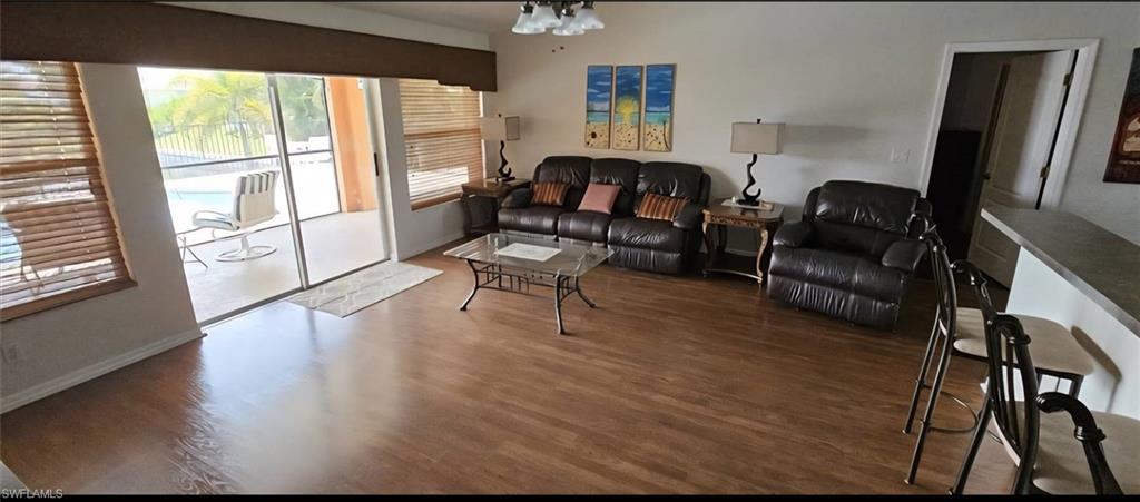 Bright living area featuring wood-finish flooring and a glass slider to the screened outdoor area