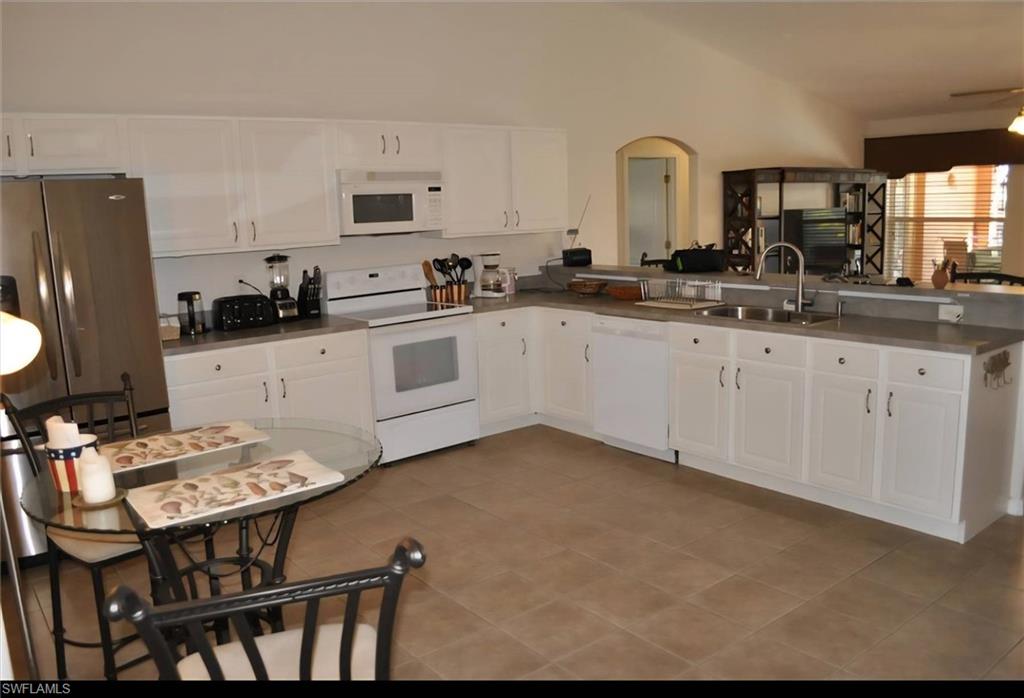 Spacious kitchen featuring extensive white cabinetry, a double basin sink, and a full suite of appliances