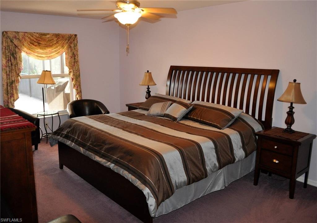 Carpeted bedroom featuring a window with decorative valance, a ceiling fan with light fixture, and light-toned walls