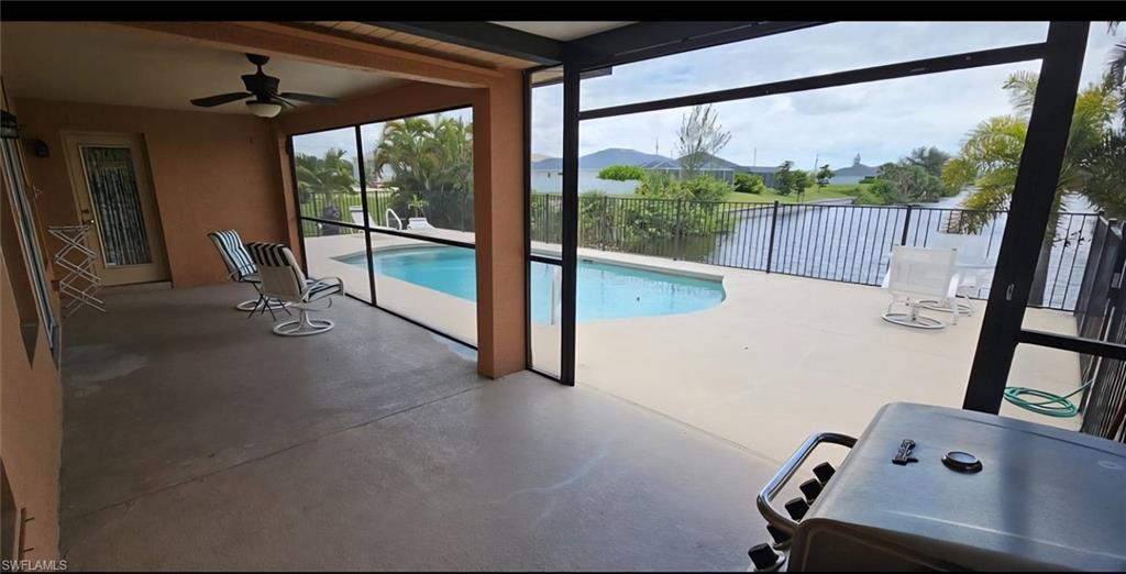 Screened-in patio with concrete flooring, featuring a ceiling fan and direct access to an outdoor swimming pool