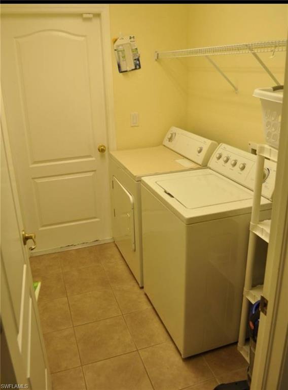 Dedicated laundry area featuring ceramic tile flooring, neutral wall tones, and a wall-mounted wire shelf for organization