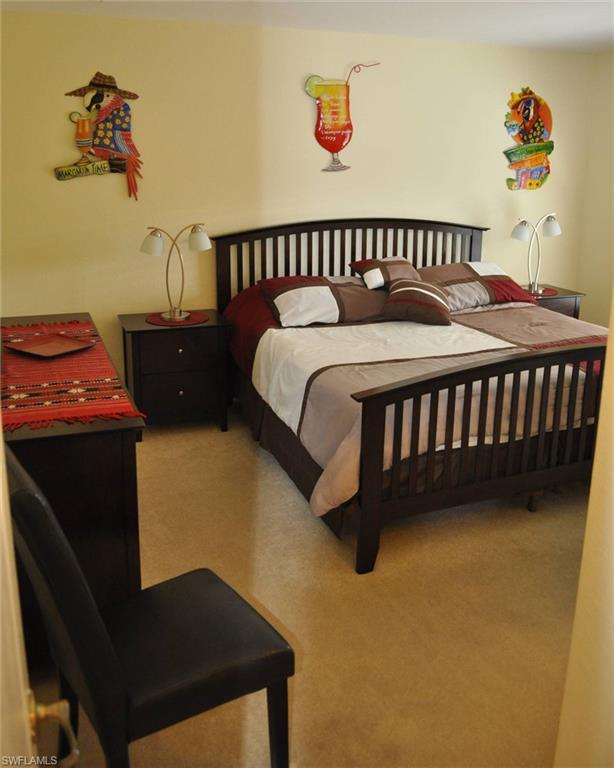 Carpeted room featuring a dark wood-finish bed frame with a slatted headboard and footboard