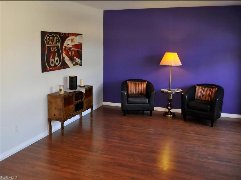 Rich wood-finish flooring complements the vibrant accent wall, creating a dynamic space