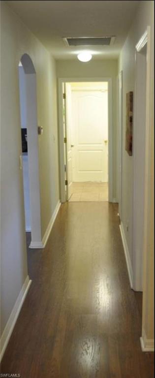 Hallway featuring wood-finish flooring, white baseboards, and neutral wall tones
