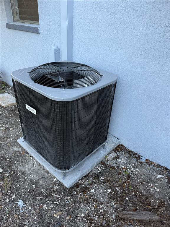 Exterior air conditioning unit on a concrete pad, positioned against a textured stucco wall