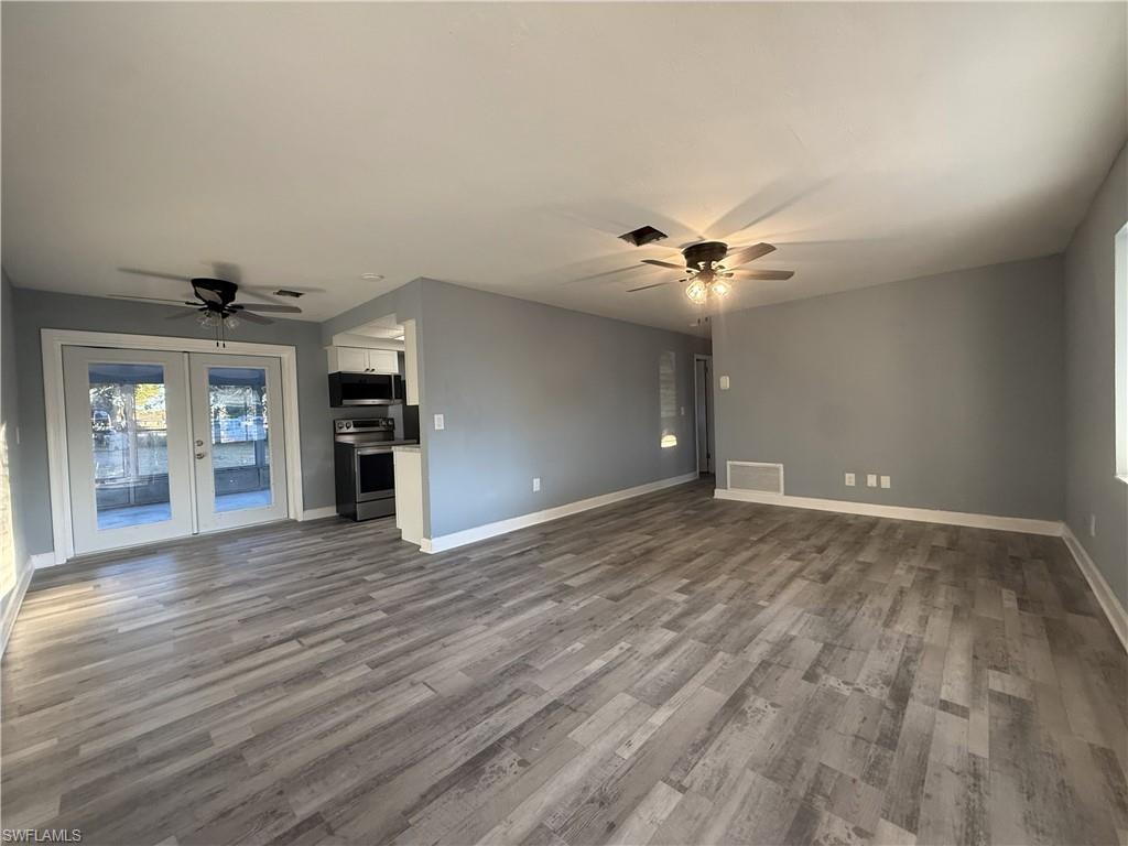Spacious living area featuring wood-finish flooring, neutral gray wall tones, and white trim