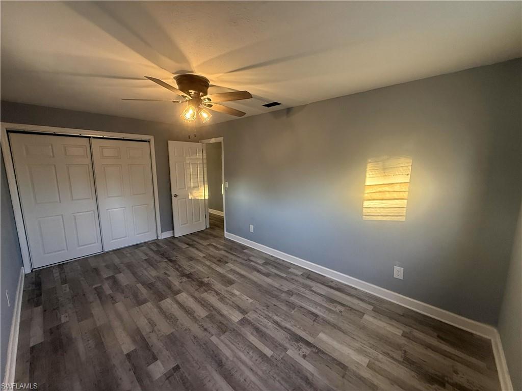 Spacious room featuring wood-finish flooring, light gray wall paint, and white baseboards