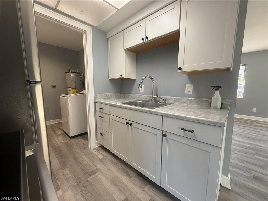 Kitchenette featuring light gray cabinetry with black hardware, a stainless steel sink with a gooseneck faucet, and a light gray countertop