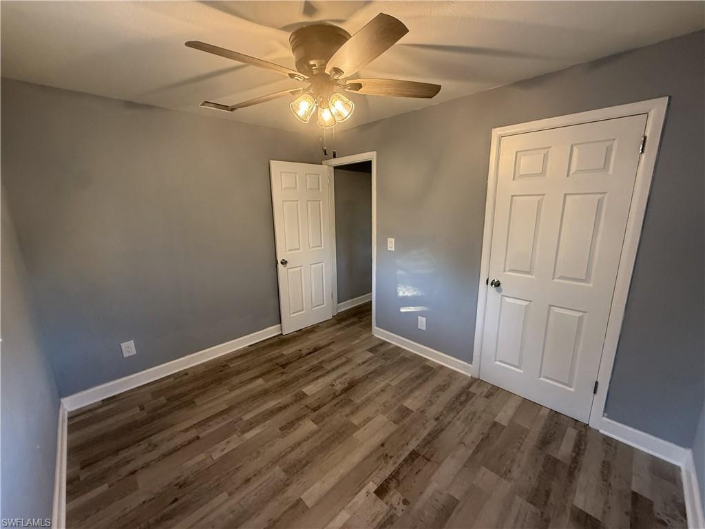 Room featuring wood-finish flooring, neutral gray walls, and white trim