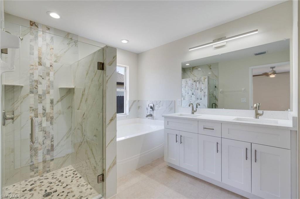 Walk-in shower with clear glass enclosure, dual built-in shelving, and mosaic tile accents