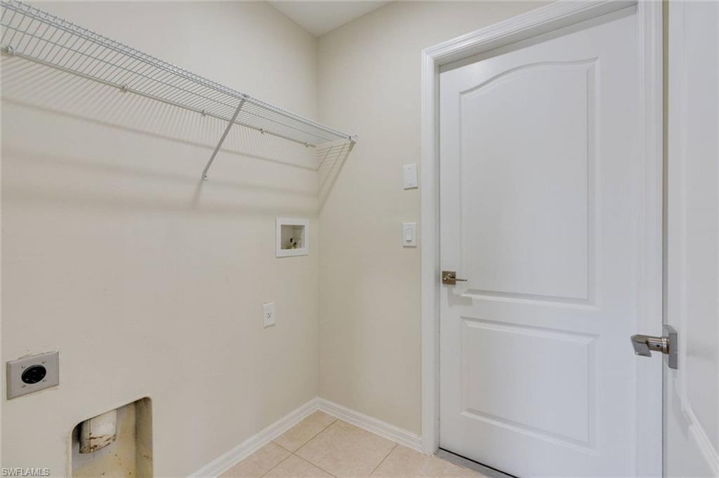 Utility room featuring a wire shelving unit, tile flooring, and a paneled door with brushed nickel hardware
