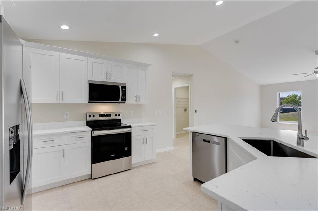 Kitchen featuring white cabinetry, stainless steel appliances, a large island with an undermount sink, and recessed lighting