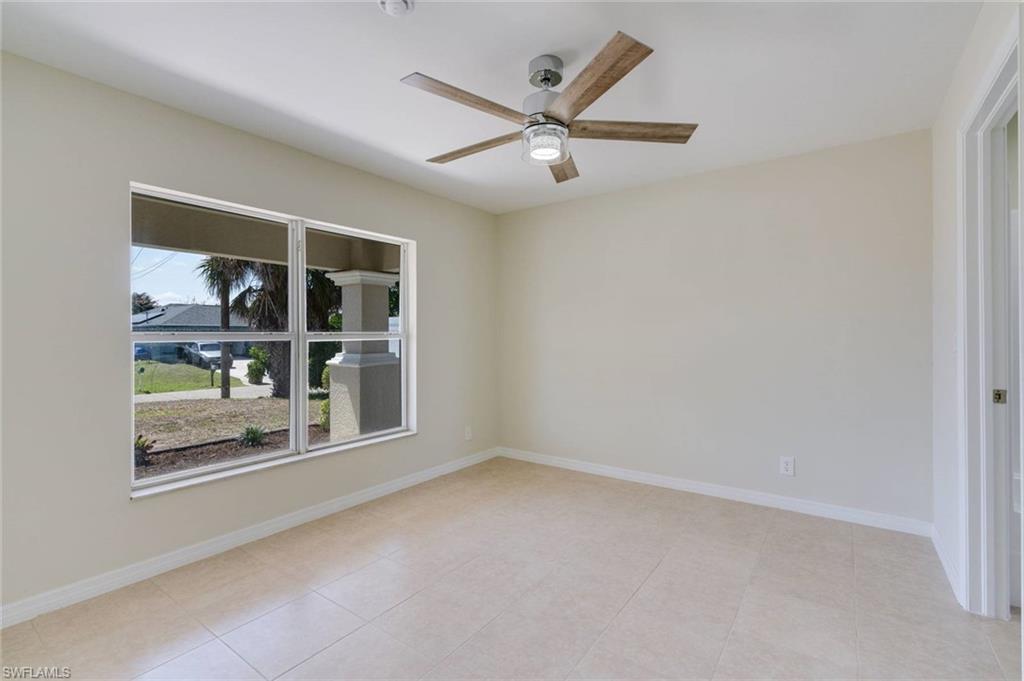 Tiled flooring, white wall paint, window with white trim, and a ceiling fan with light fixture