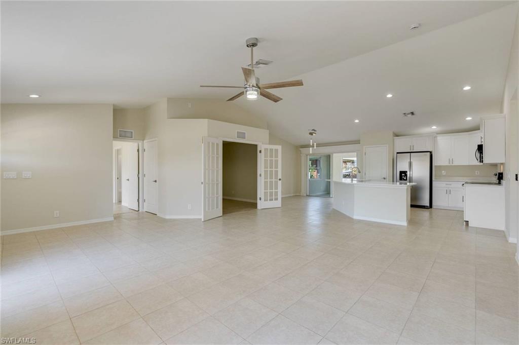 Spacious open-concept living area featuring tile flooring, vaulted ceilings, and recessed lighting