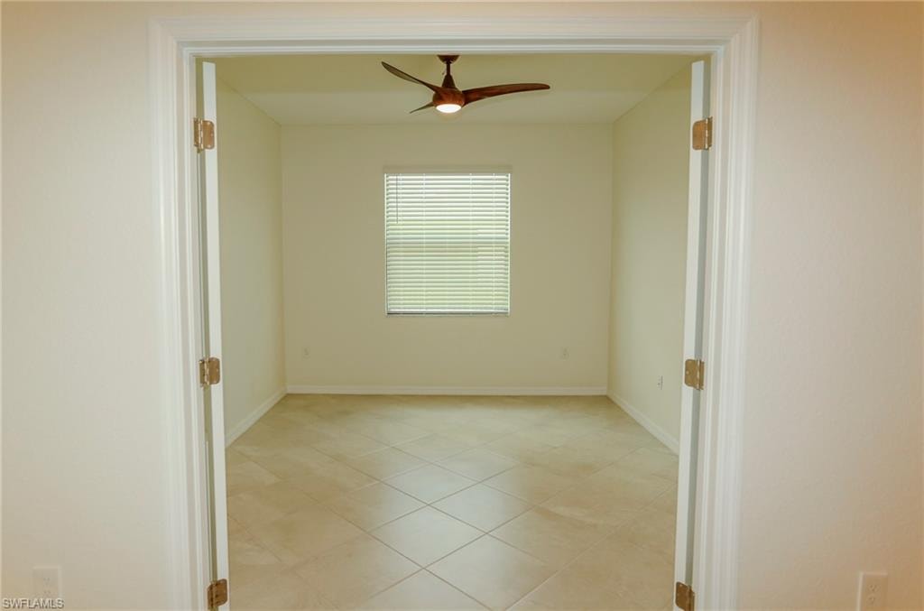 Room with neutral wall color, tile flooring, and a ceiling fan