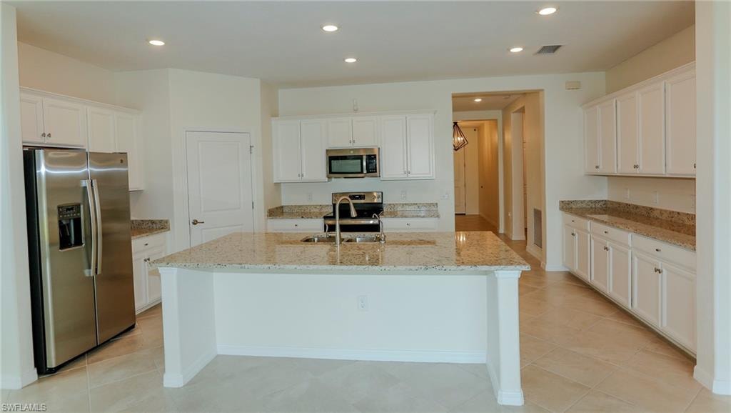 Expansive kitchen featuring a large center island, white cabinetry, integrated stainless steel appliances, and recessed lighting