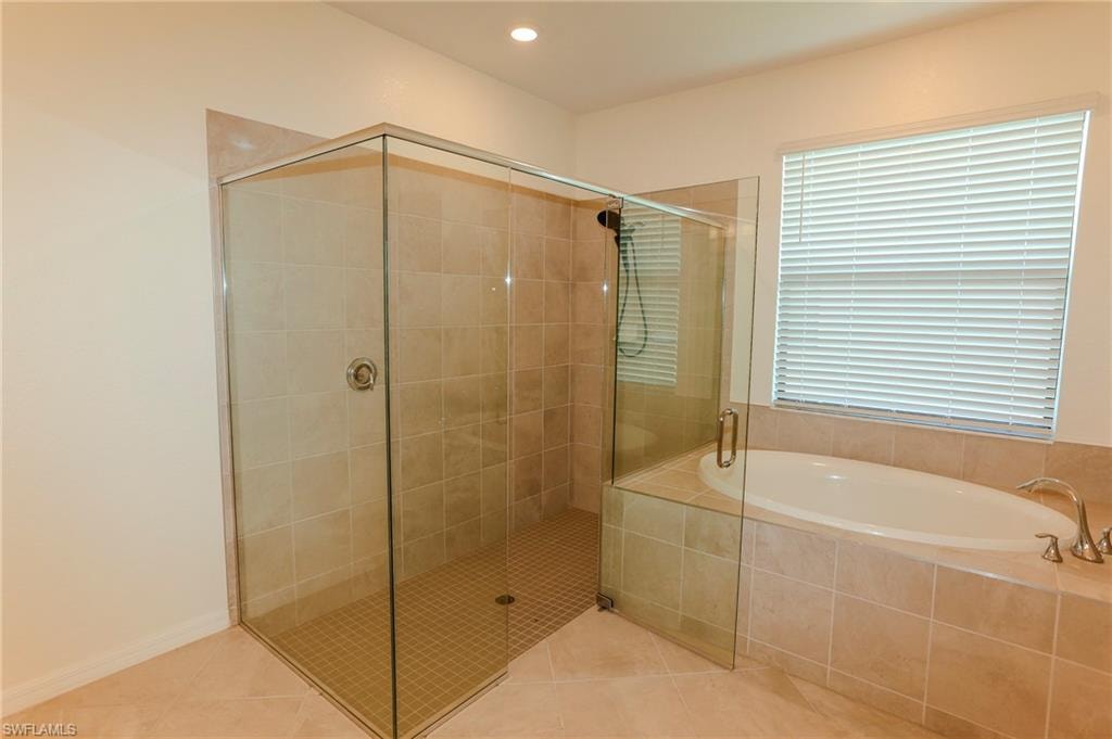 Glass-enclosed shower with tiled walls and floor, soaking tub with tiled surround, and recessed lighting