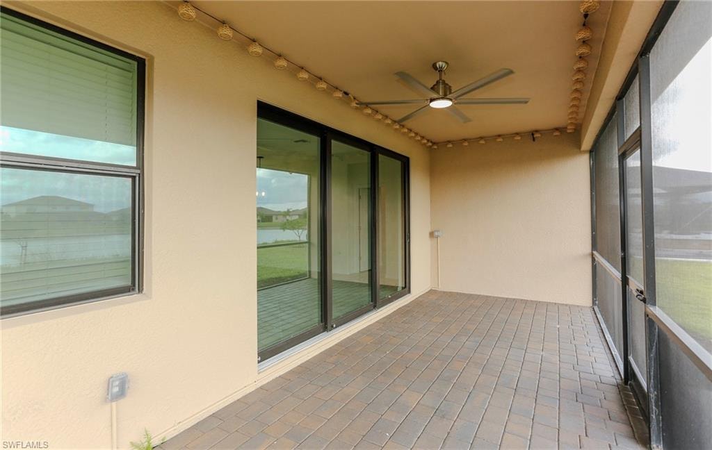 Covered patio featuring brick paver flooring, a ceiling fan, and screened enclosure