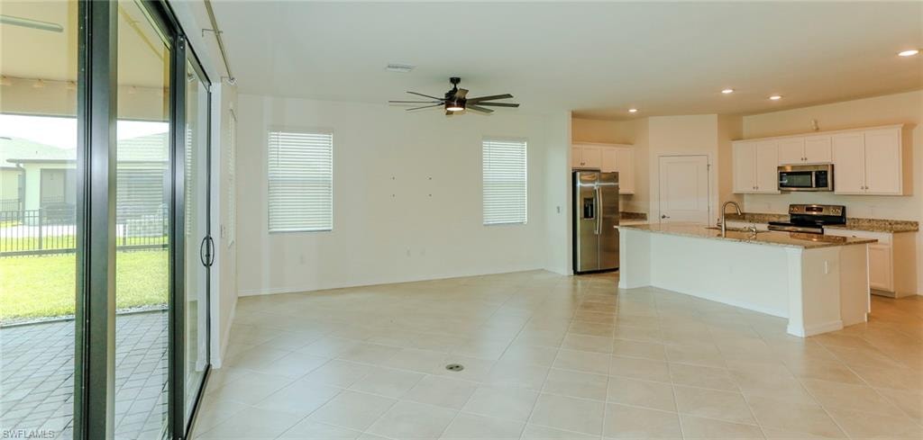 Open-concept living space featuring neutral tile flooring and a ceiling fan