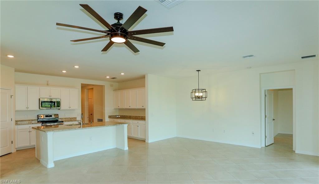 Open-concept design featuring tile flooring, white cabinetry, stainless steel appliances, and granite countertops
