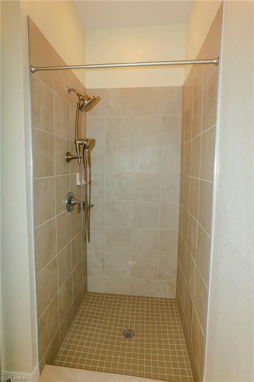 Tile shower with a brushed nickel showerhead and handheld sprayer