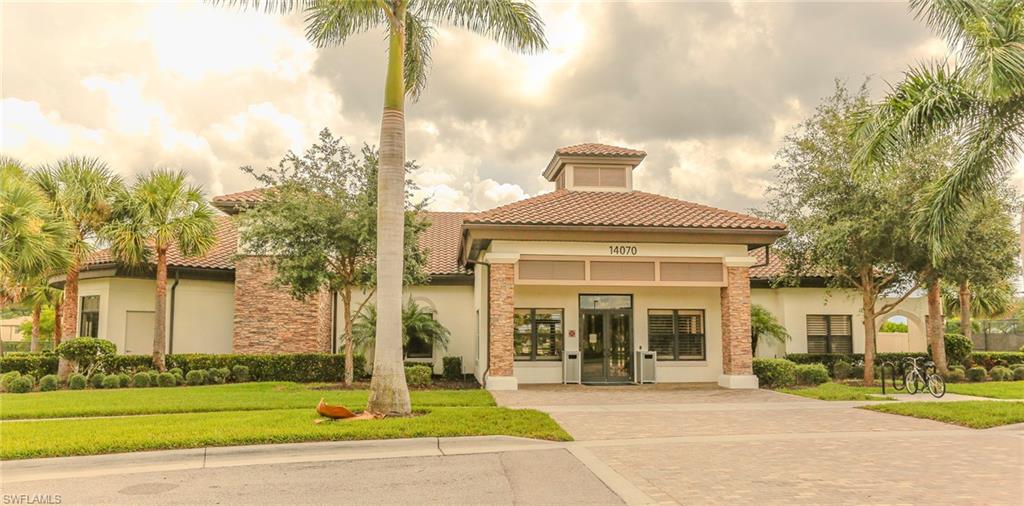 Mediterranean-style building featuring a tile roof, light stucco exterior, and brick column accents