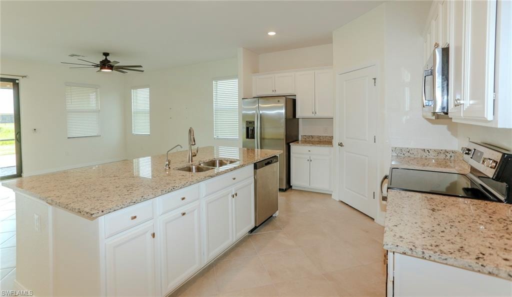 Kitchen featuring a large central island with double sink, white cabinetry, granite countertops, and stainless steel appliances