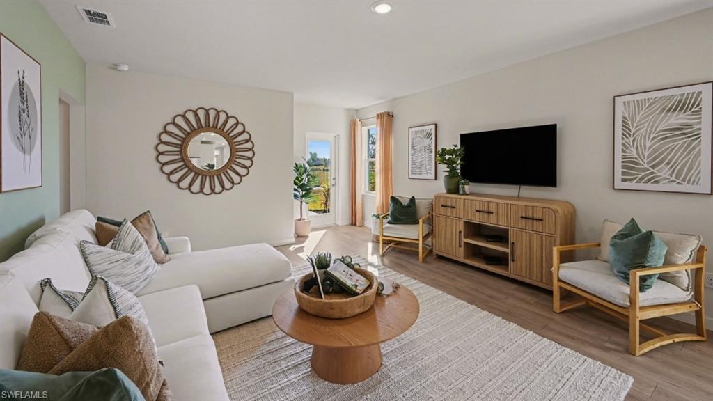 Spacious living area featuring light wood-finish flooring and recessed lighting
