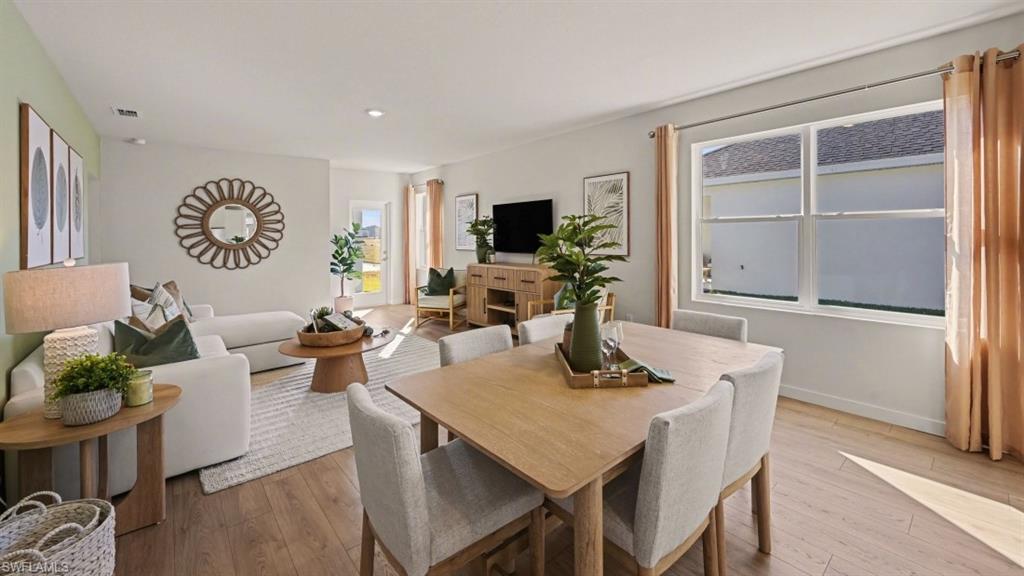 Open-concept living and dining area featuring wood-finish flooring, recessed lighting, and a neutral color palette