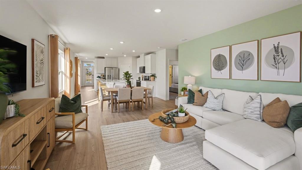Spacious open-concept living area featuring wood-finish flooring, recessed lighting, multiple windows, and a dedicated dining space