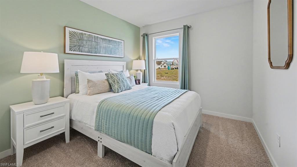 Bedroom featuring neutral carpeting, a window with exterior views, and a wall with a subtle green accent color