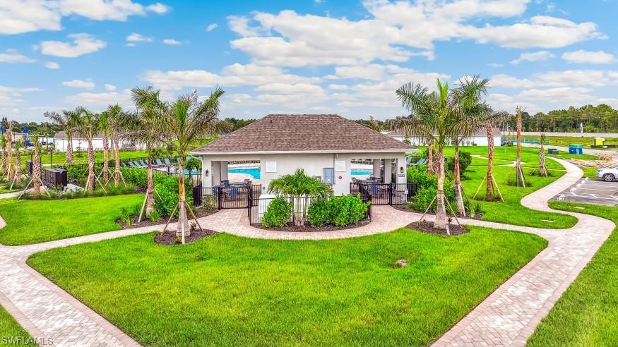 Community amenity building featuring a covered patio, a swimming pool, and surrounding green spaces with palm trees and paved walkways