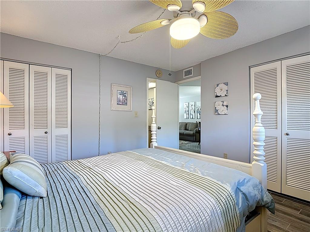Bedroom featuring a ceiling fan, wood finished floors, a textured ceiling, and two closets