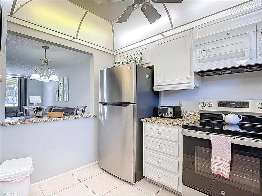 Kitchen with appliances with stainless steel finishes, white cabinetry, light stone counters, and light tile patterned floors