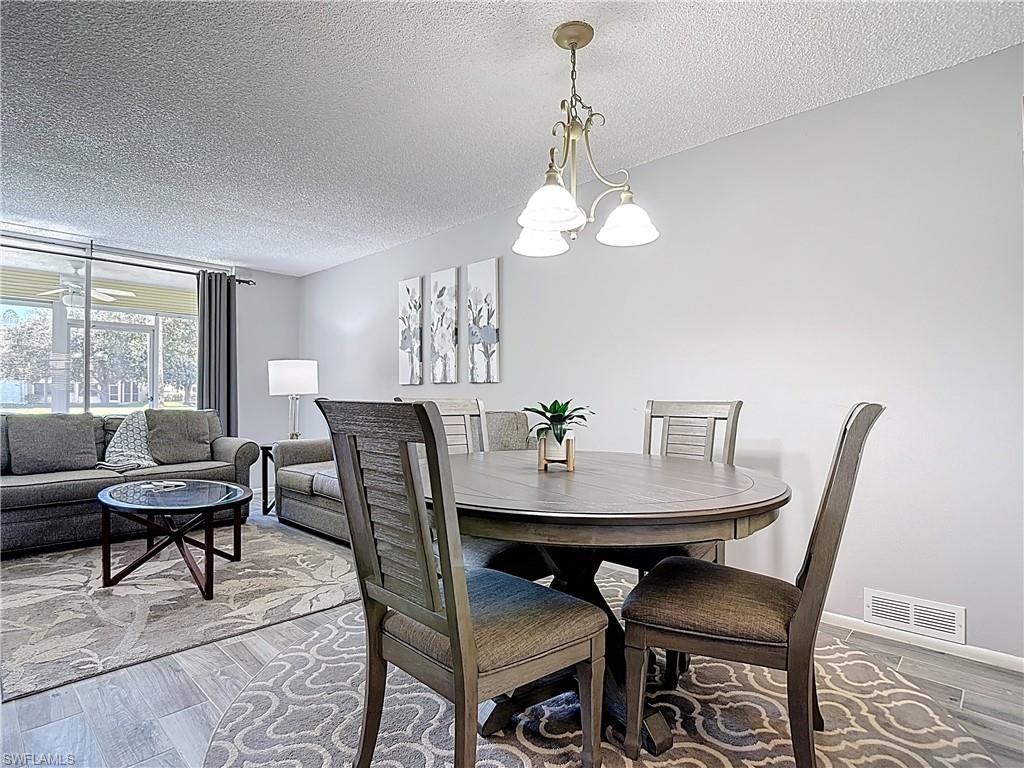 Dining room with a textured ceiling, wood finished floors, and a chandelier
