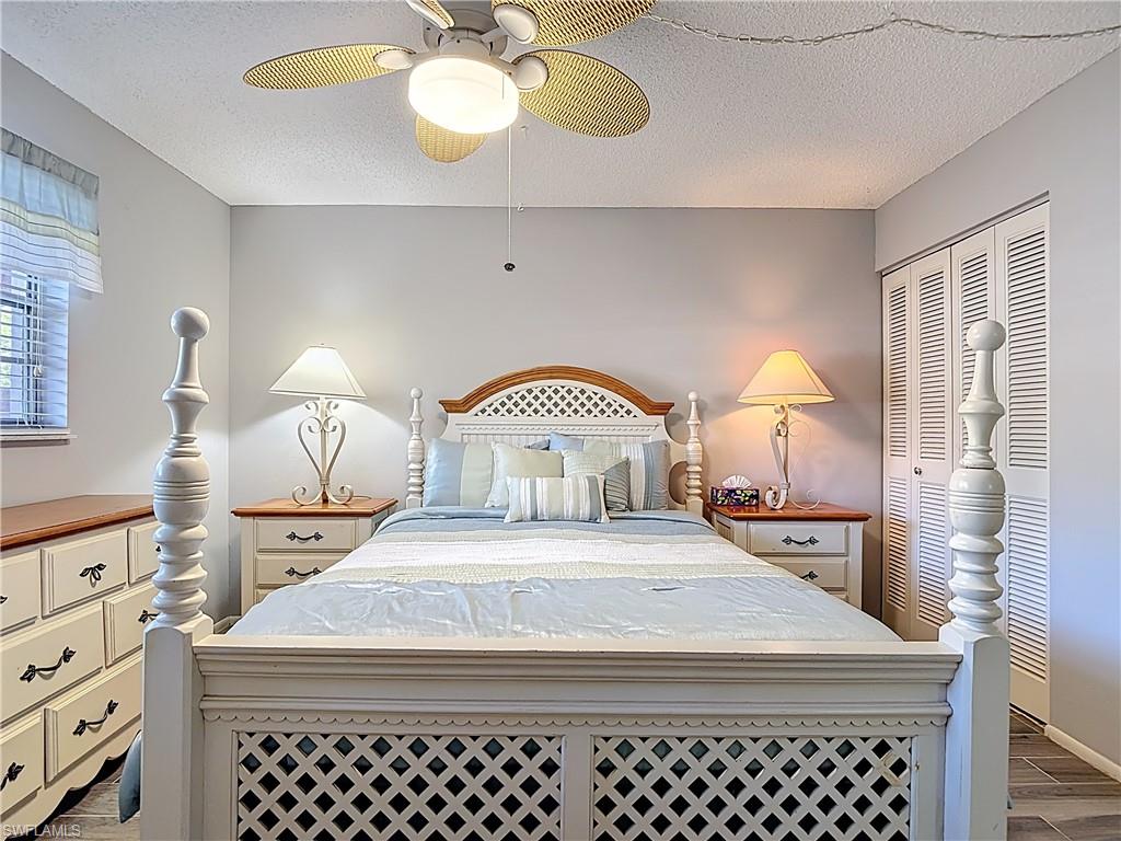 Bedroom with dark wood finished floors, a textured ceiling, a ceiling fan, and a closet