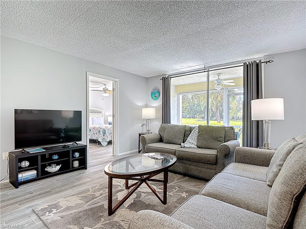 Living area with ceiling fan, wood finished floors, and a textured ceiling