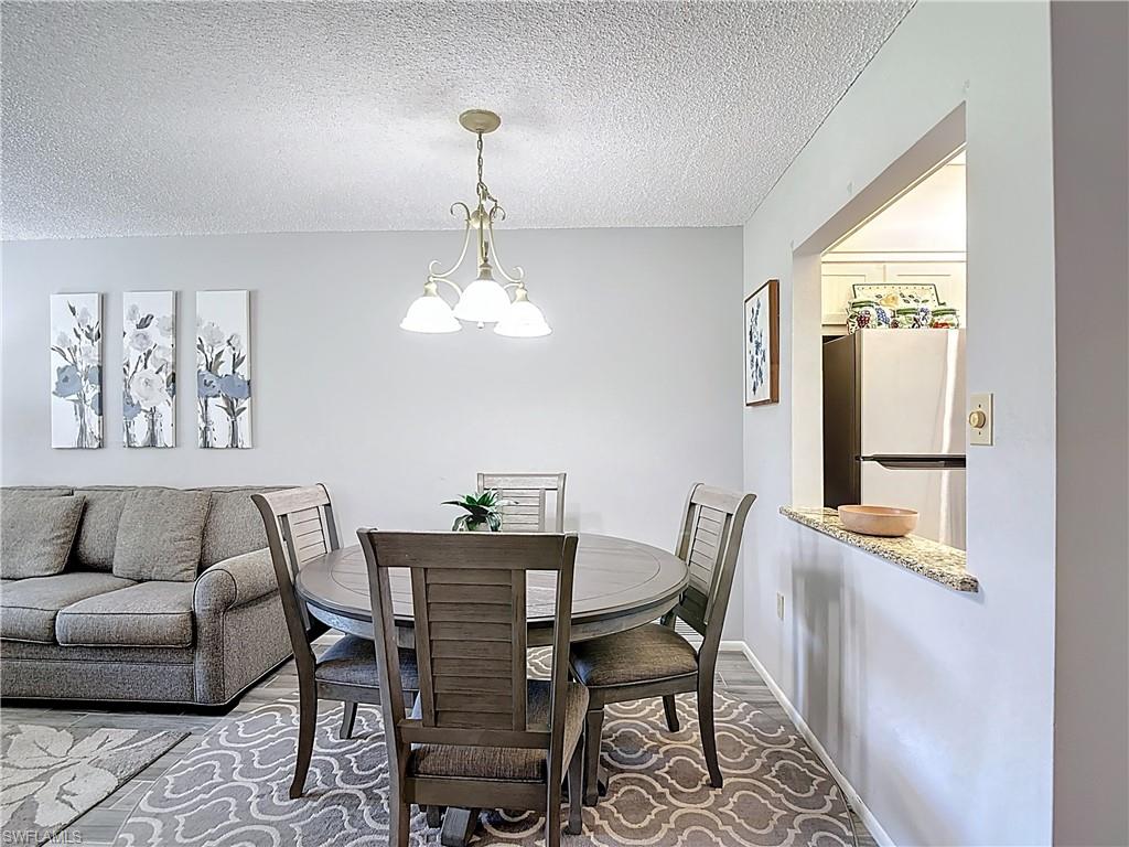 Dining space with a textured ceiling, a chandelier, and wood finished floors
