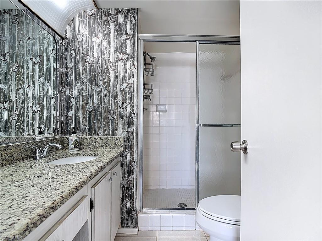 Full bath featuring a shower stall, light tile patterned floors, and vanity