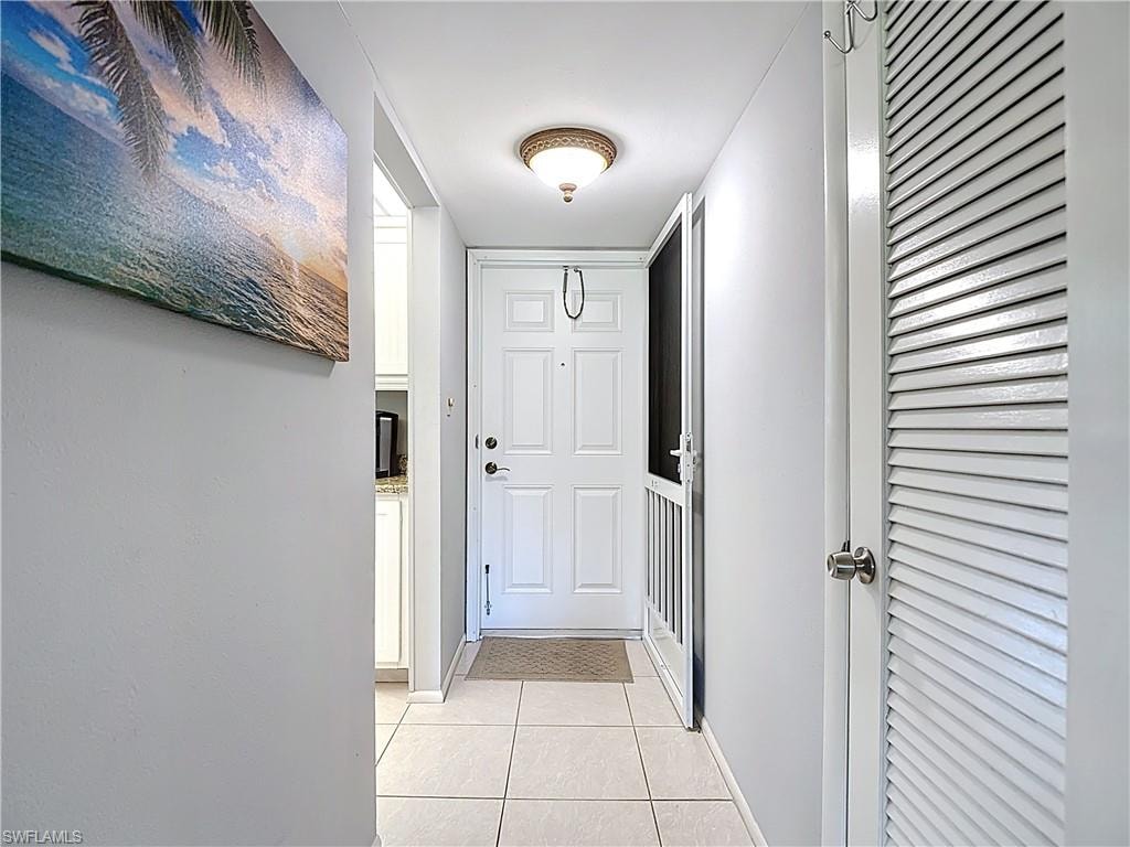 Doorway with tile patterned floors and baseboards