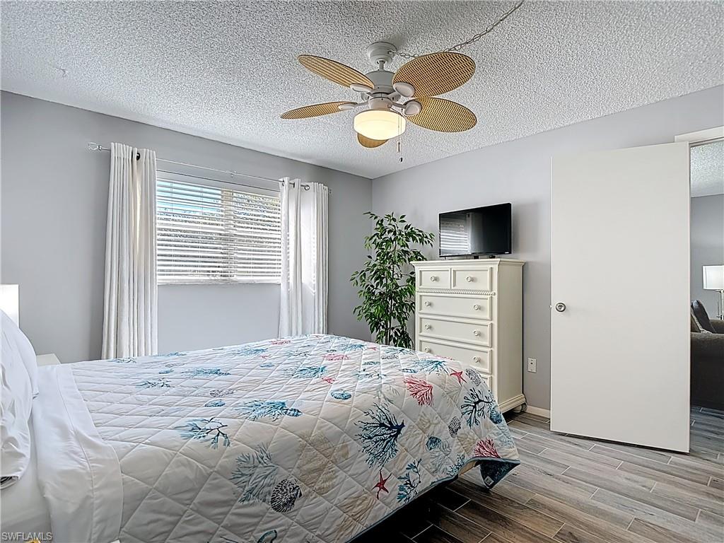 Bedroom with a textured ceiling, wood finish floors, and a ceiling fan