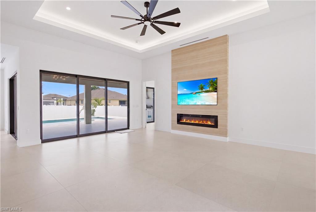 Spacious open-concept living room with soaring tray ceilings and modern recessed lighting.