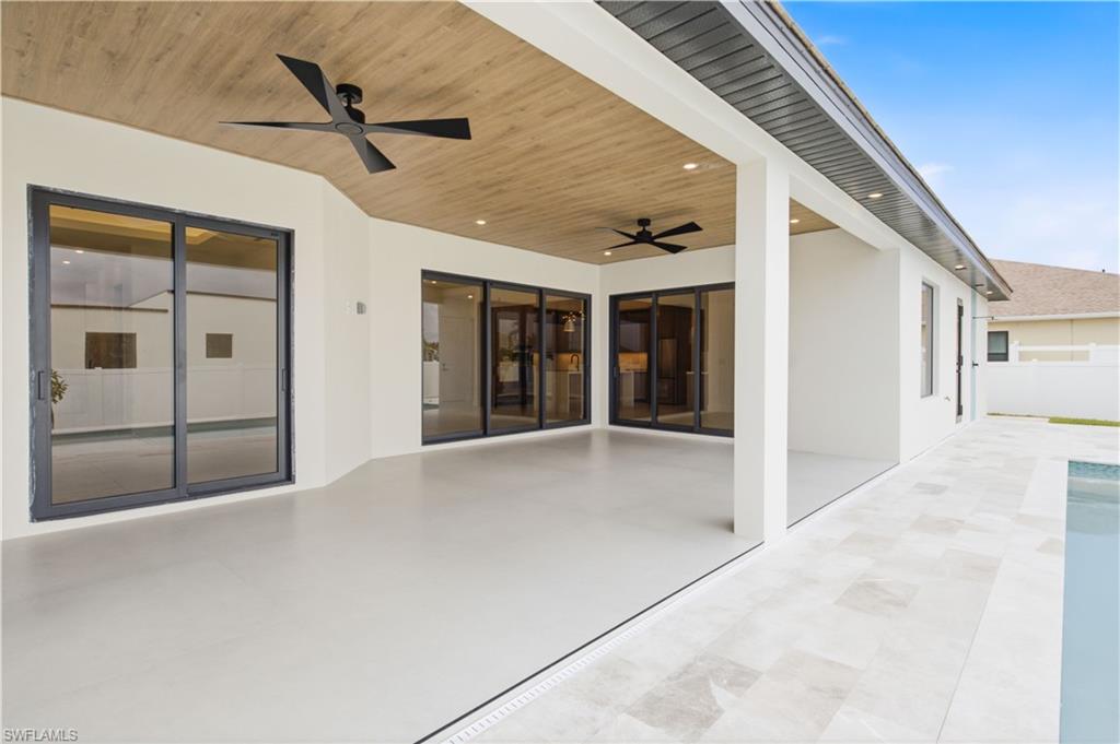 Expansive covered patio with wood-accent ceiling and dual fans offers a stylish space for year-round outdoor living.