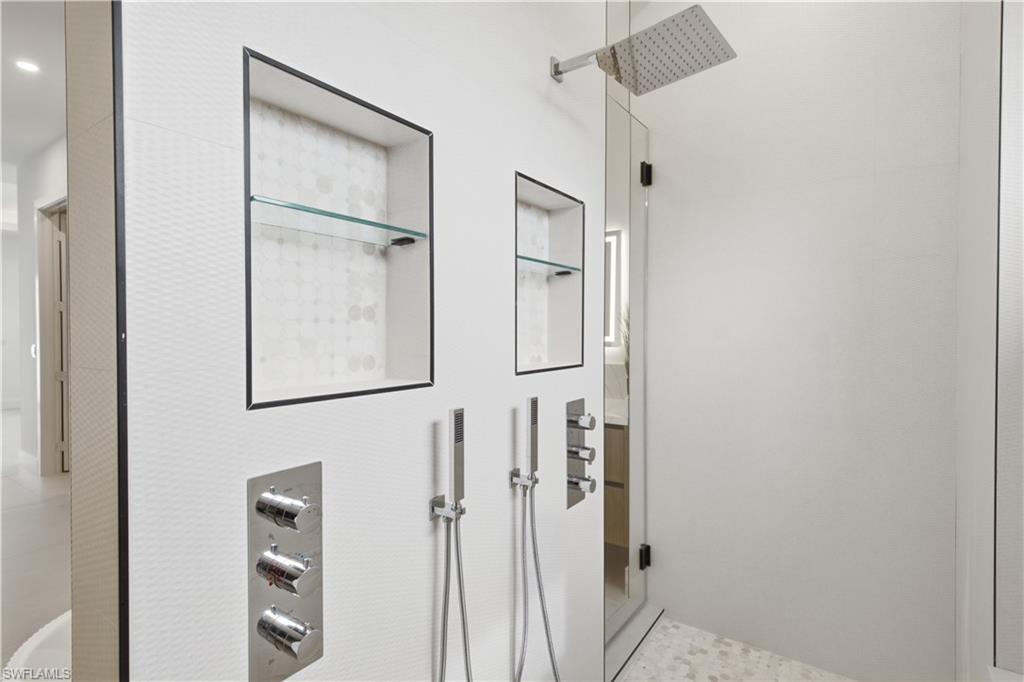 Oversized glass-enclosed shower offers a rainfall showerhead, dual handheld fixtures and multiple body jets.