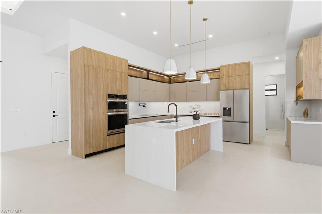 Chef-inspired gourmet kitchen showcasing sleek European-style custom cabinetry, Taj-Mahal inspired quartz countertops w/ waterfall island
